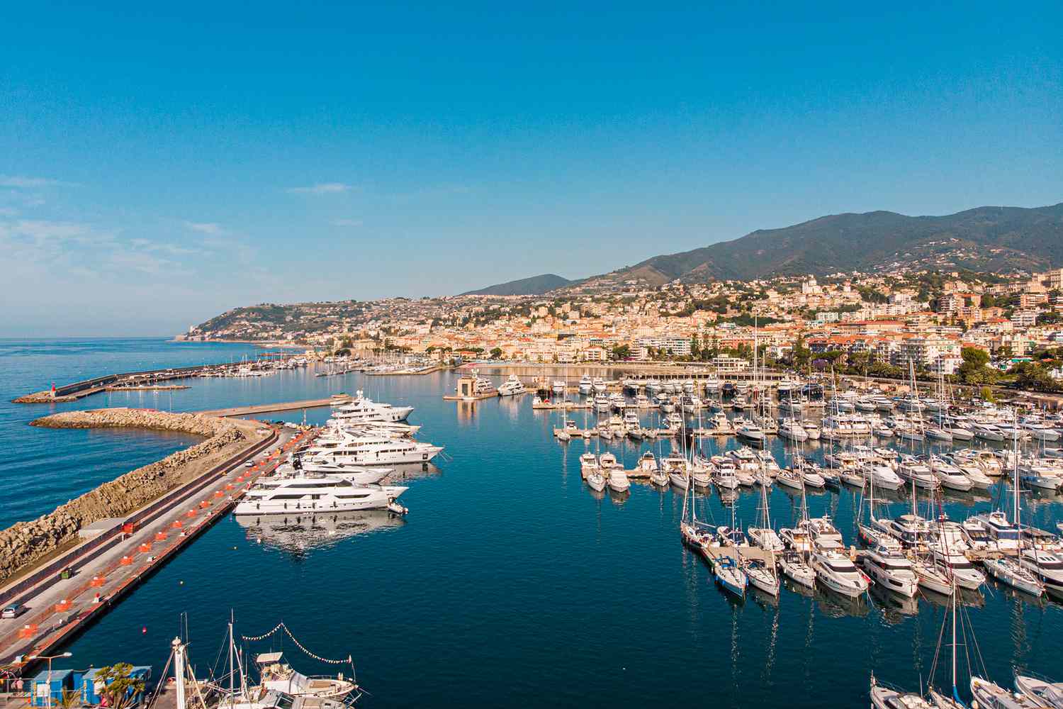 View of Sanremo harbor in Italy, with luxury yachts and colorful buildings along the Ligurian coastline.