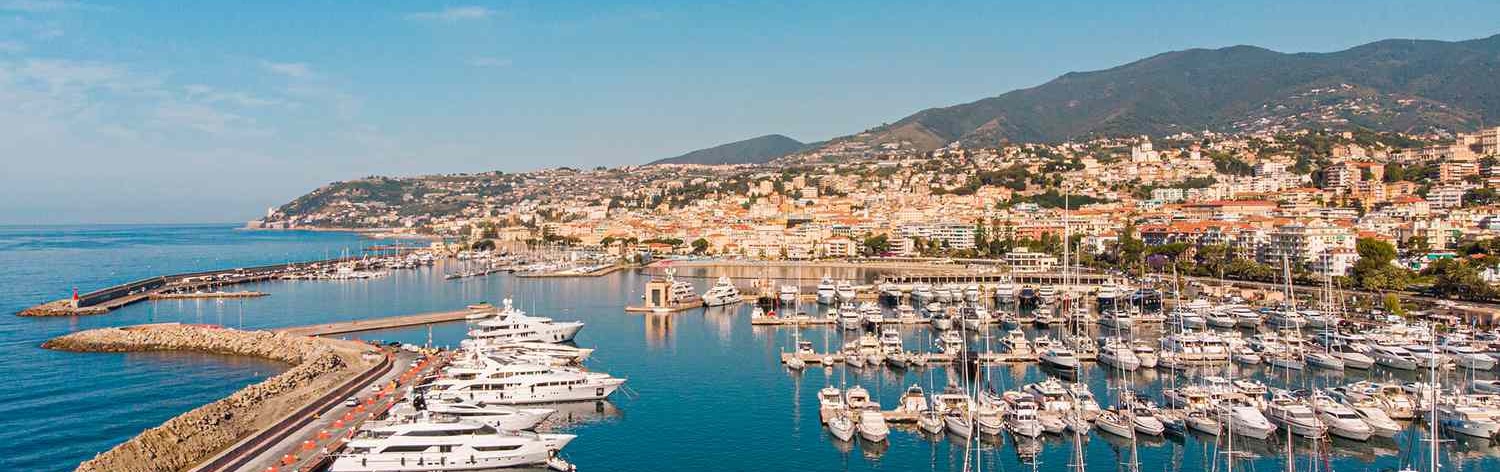 View of Sanremo harbor in Italy with yachts docked along the Ligurian coastline.