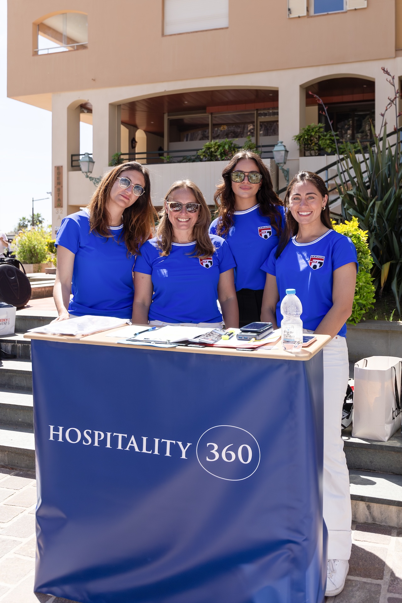 Four event hostesses wearing blue polo shirts at the Hospitality 360 event in Monaco.