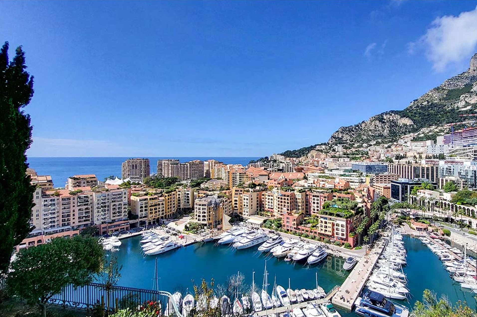 View of Monaco marina with luxury yachts docked in the Mediterranean harbor.